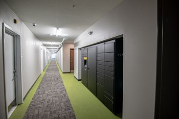 A hallway with a green carpet and a black door on the right.at Linc, Des Moines  